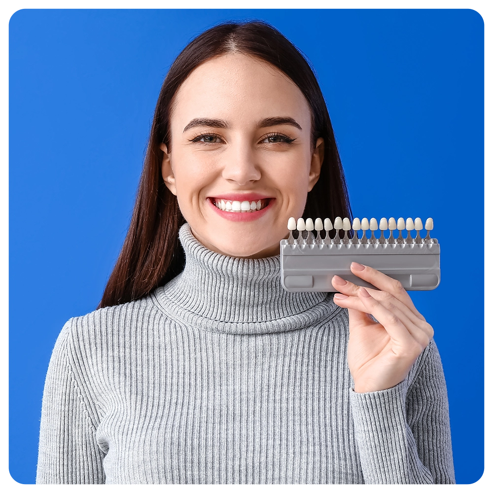 Young woman with teeth color chart on blue background