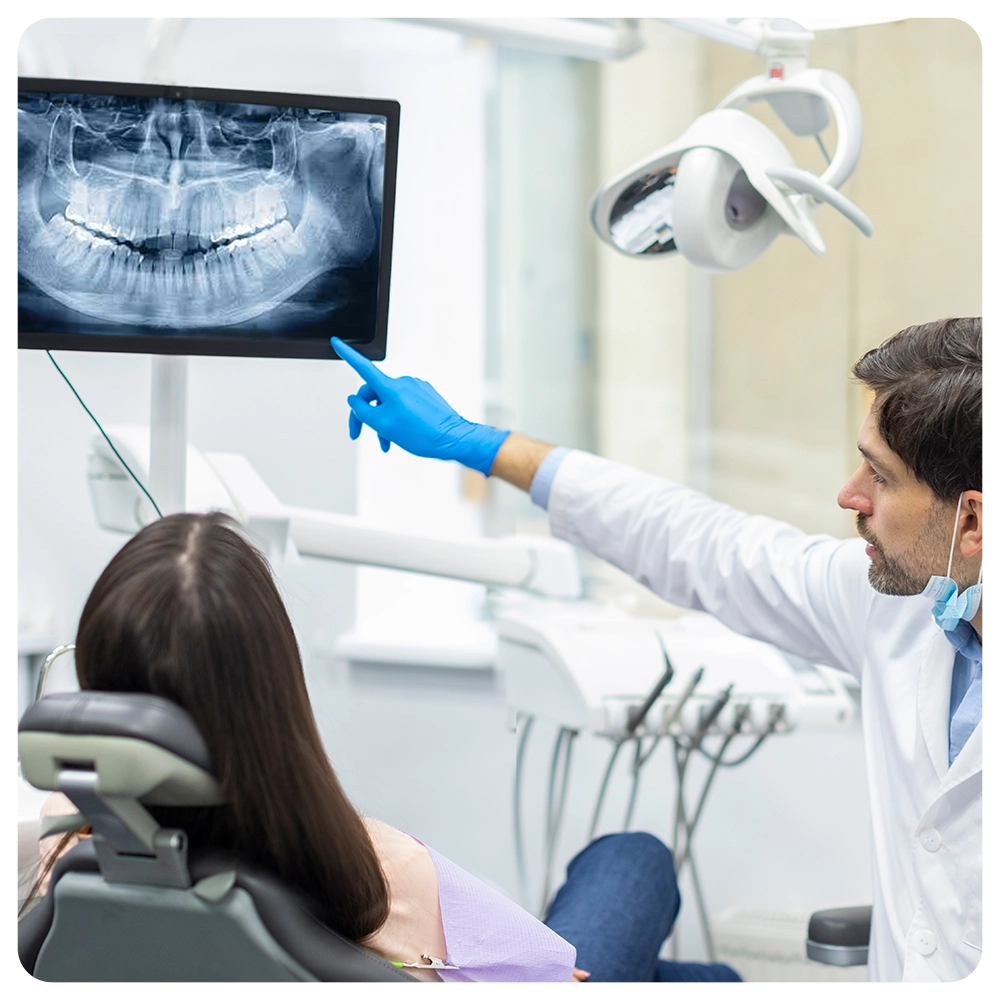 Professional male dentist showing x-ray footage of teeth to female patient in clinic office