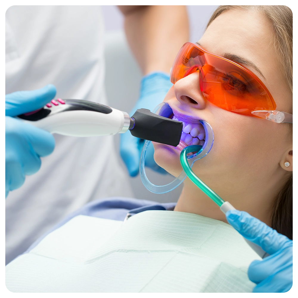 Girl patient in the dental clinic. Teeth whitening UV lamp with photopolymer composition.