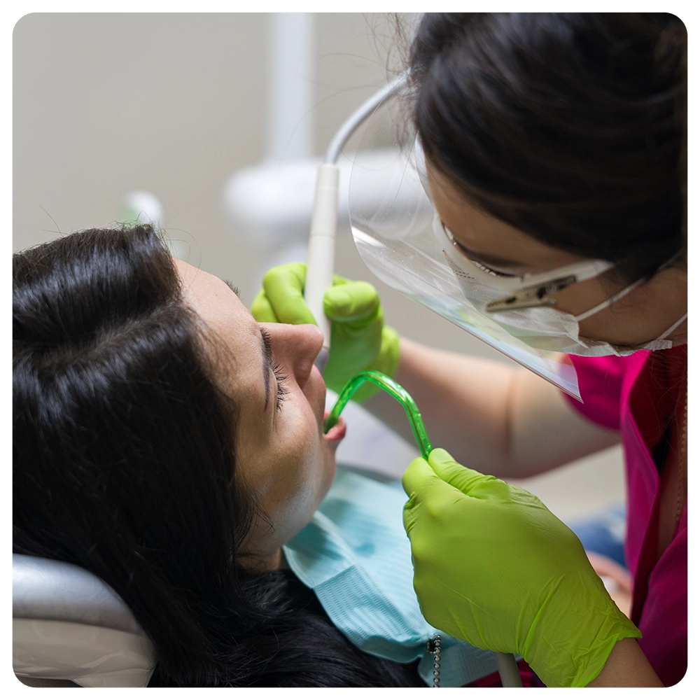 dentist cleaning teeth of woman
