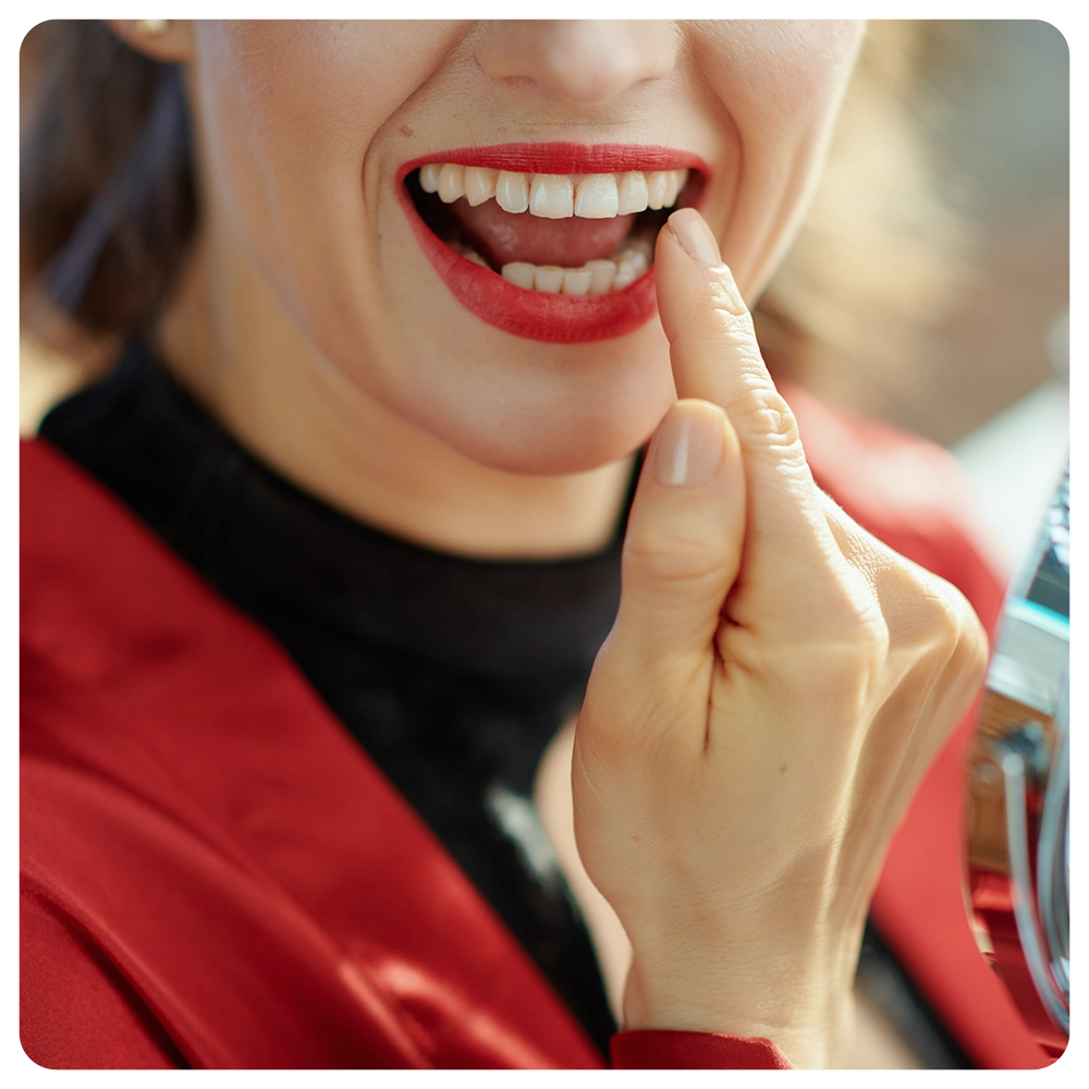 Closeup on woman in the living room in sunny day looking in mirror and checking teeth.