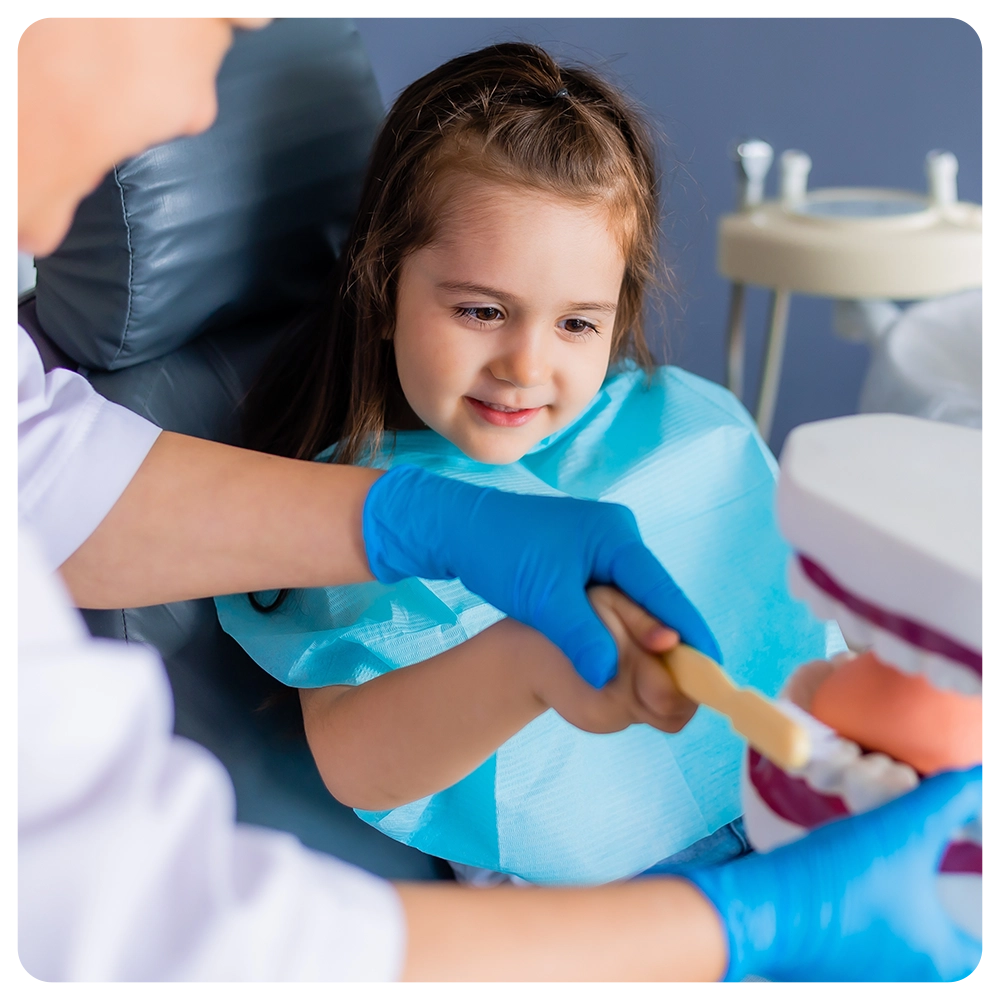 little brunette girl at a dentist's appointment studies a mannequin with a doctor, learns to brush her teeth