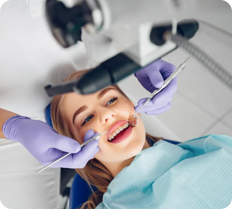 Woman receiving dental cleaning on treatment chair.