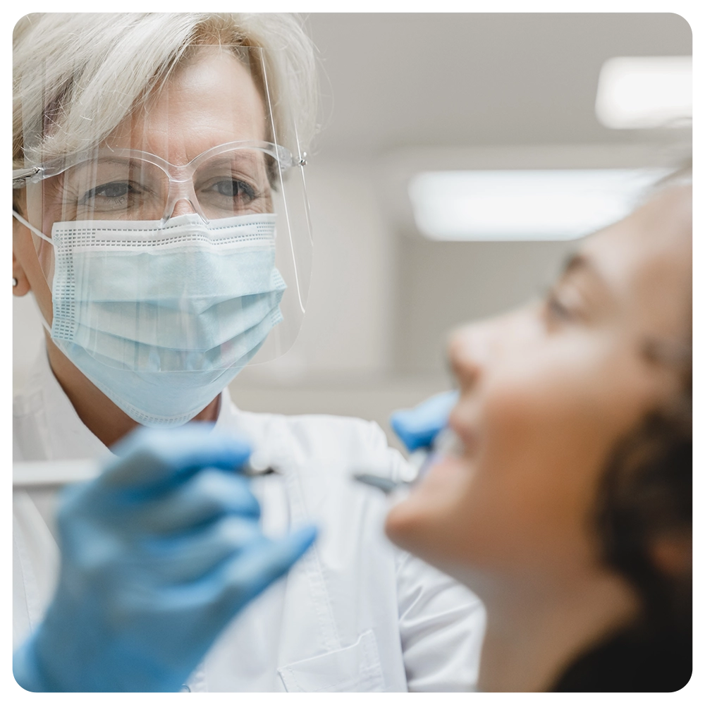 Female mature stomatologist dentist orthodont curing healing boy`s teeth tooth, doing mouth cavity cleaning, removing baby tooth