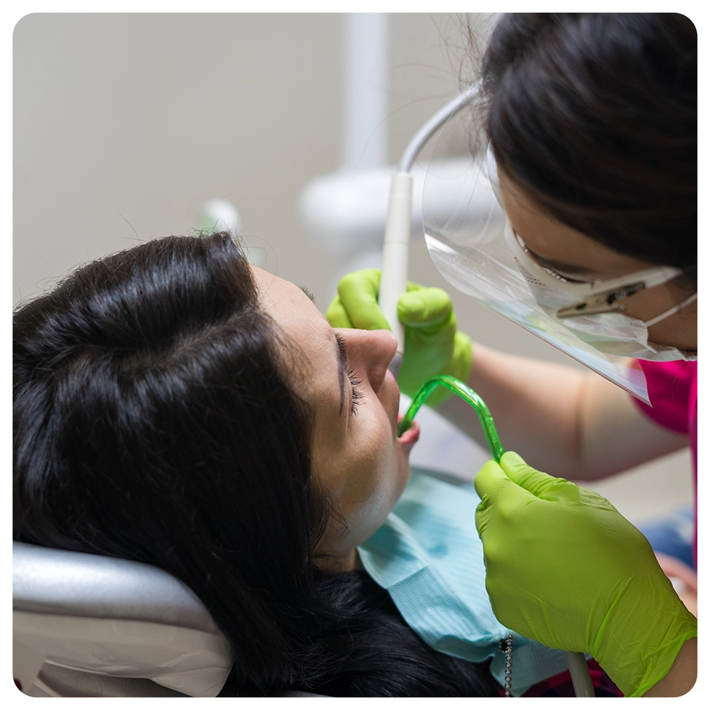 dentist cleaning teeth of woman