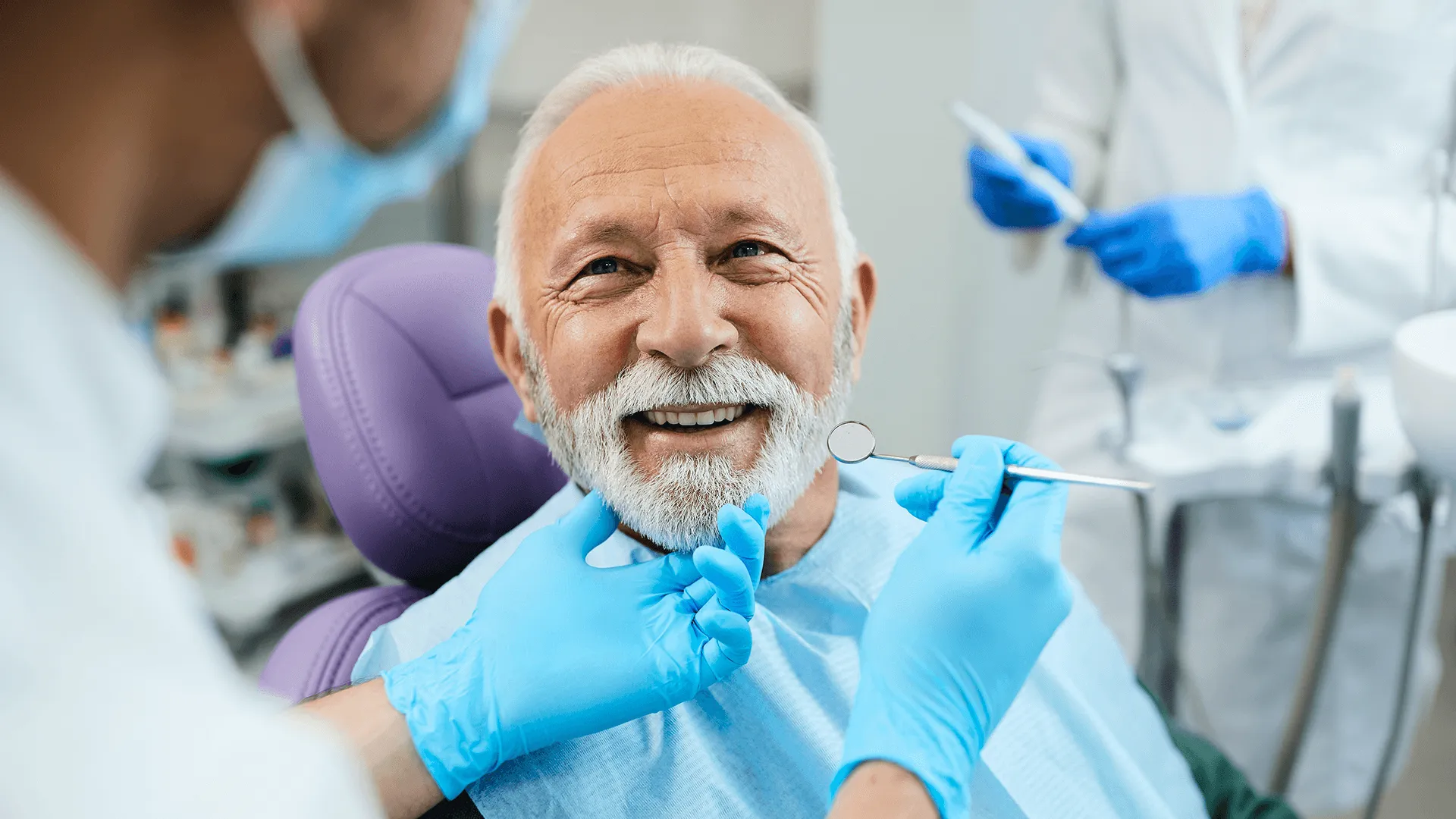 Happy mature man during teeth check-up at dental clinic.