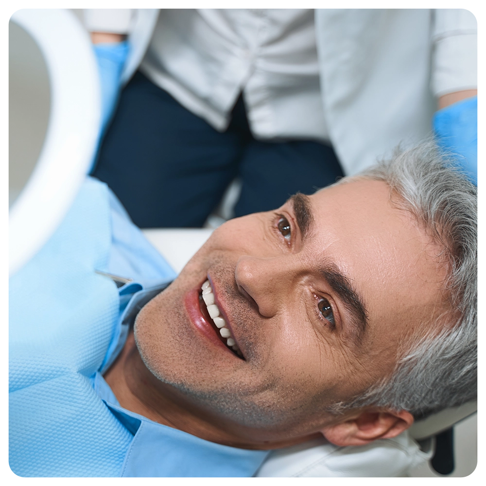 Joyful male is lying in chair and looking into mirror while being delighted with dentist work