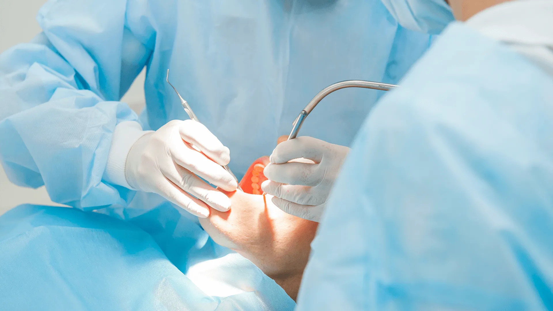 Close up dental surgery process - Implantation. Dentist surgeon with assistant in modern clinic