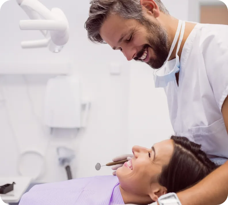 Dentist and patient smiling at each other on treatment chair.