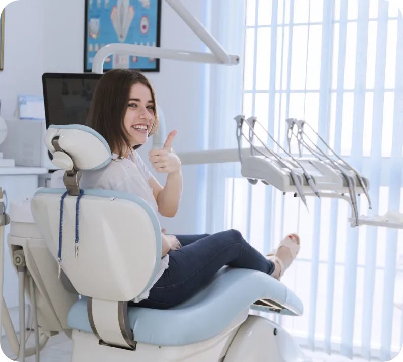 Woman on treatment chair smiling and making a thumbs-up gesture.
